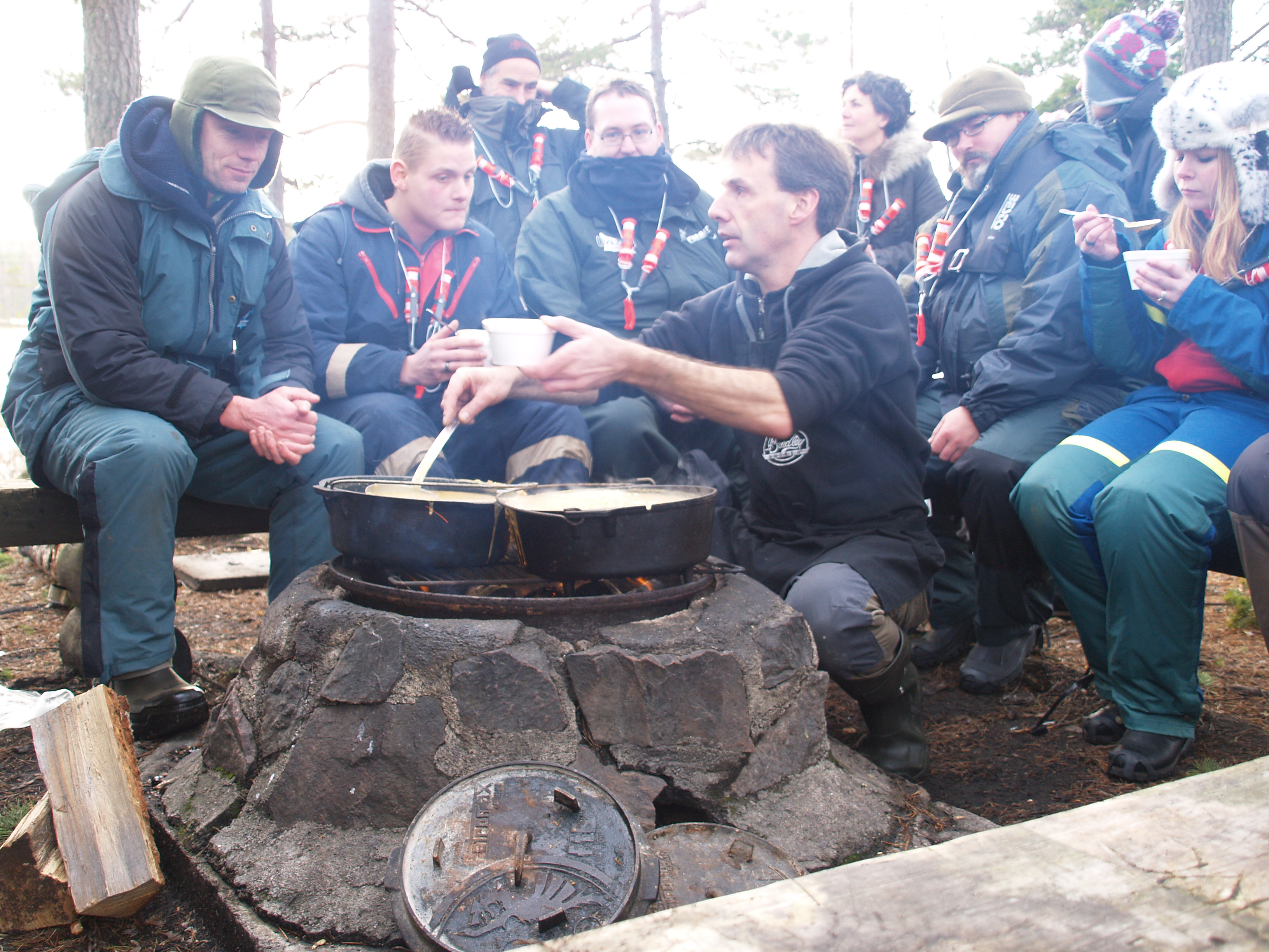 Johan Postma serviert am Lagerfeuer leckeres Essen, damit den Eisanglern wieder warm wird.